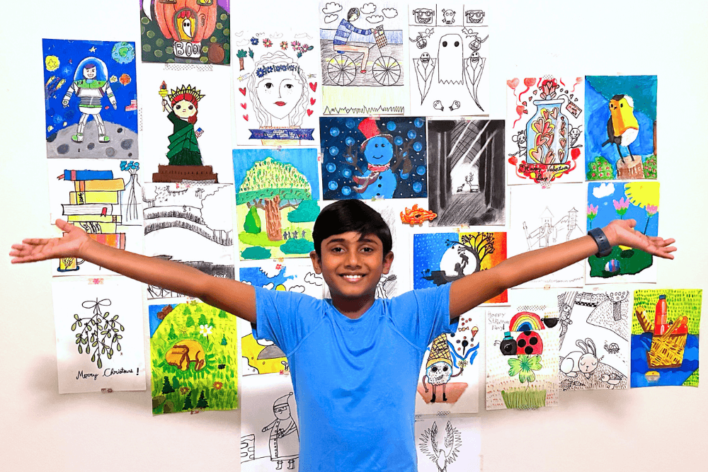 A young artist proudly displays their artwork from Nimmy's Art Classes, featuring vibrant colors and creative designs