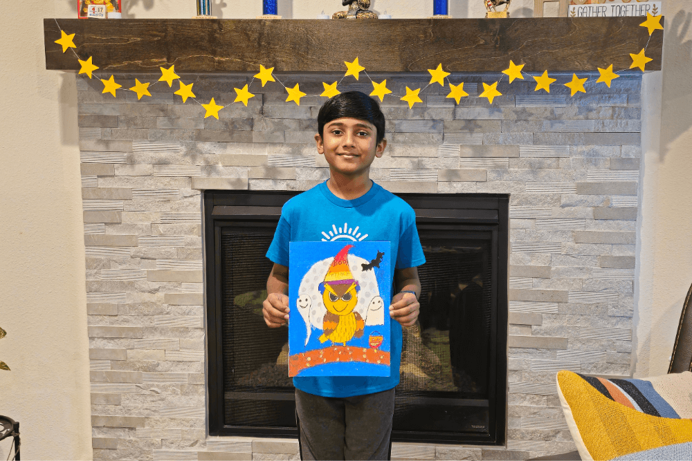 Young artist Yashwanth holds his Halloween-themed owl art made with oil pastels from Nimmy's Art Class.