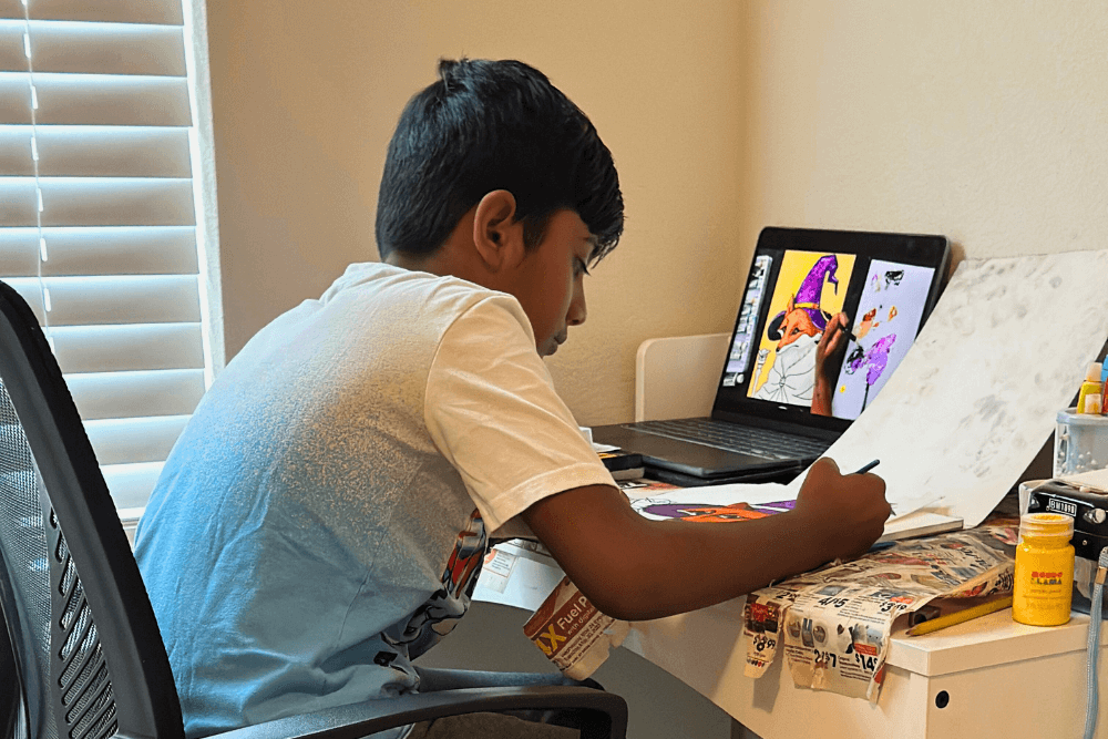 Young artist Yashwanth engages in Nimmy's online art class, surrounded by art supplies and his creations.