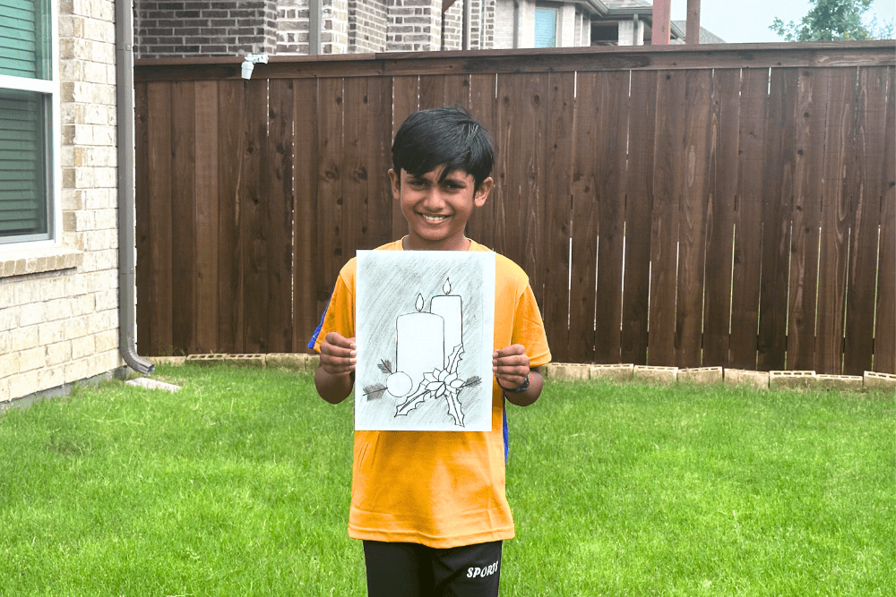 Young artist Yashwanth holds his charcoal drawing 'Holiday Candles,' showcasing his talent and creativity