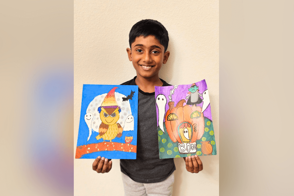 Young artist Yashwanth holding his acrylic painting 'Haunted Pumpkin Castle,' depicting a spooky and imaginative scene.