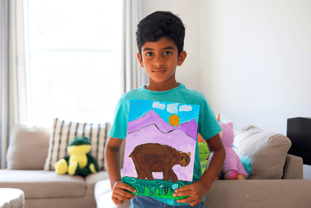 George proudly holding his colorful painting of a bear