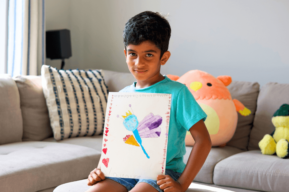 George proudly holding his colorful dragonfly painting, showcasing vibrant hues and intricate details.