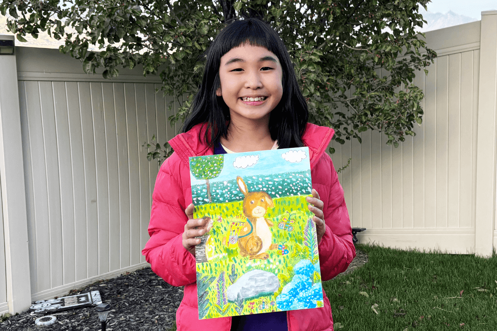 Bella proudly holding her watercolor painting of an Easter Bunny.