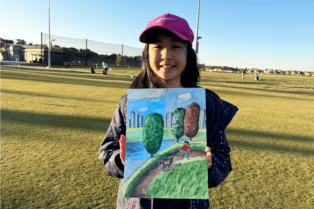 Bella proudly holding her painting, Girl Walking a Dog, showcasing her creativity and artistic talent.